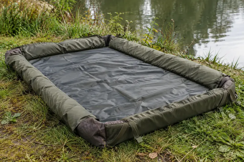 Tapis de réception de pêche déplié sur l’herbe près de l’eau