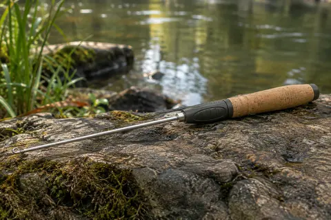 Dégorgeoir Guru Conti à profil long et fin posé au bord d’une rivière calme