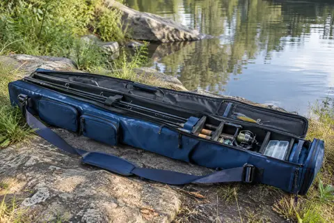 Fourreau de pêche bleu à trois compartiments, avec poches extérieures et bandoulière réglable, posé au bord de l’eau.
