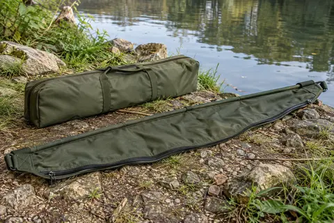 Sangle de pesée verte pour carpe avec fermetures latérales et étui, posée au bord d’une rivière