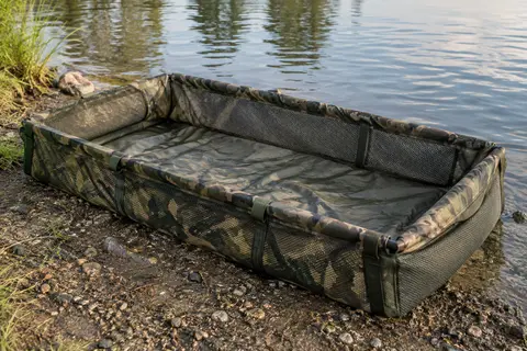 Tapis de réception Ultimate à rebords relevés et ouvertures en maille, posé sur une rive calme.