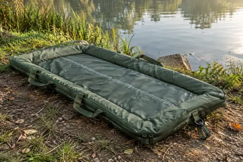 Tapis de réception vert rembourré avec poignées, fermeture éclair et repère de mesure près d’une rivière